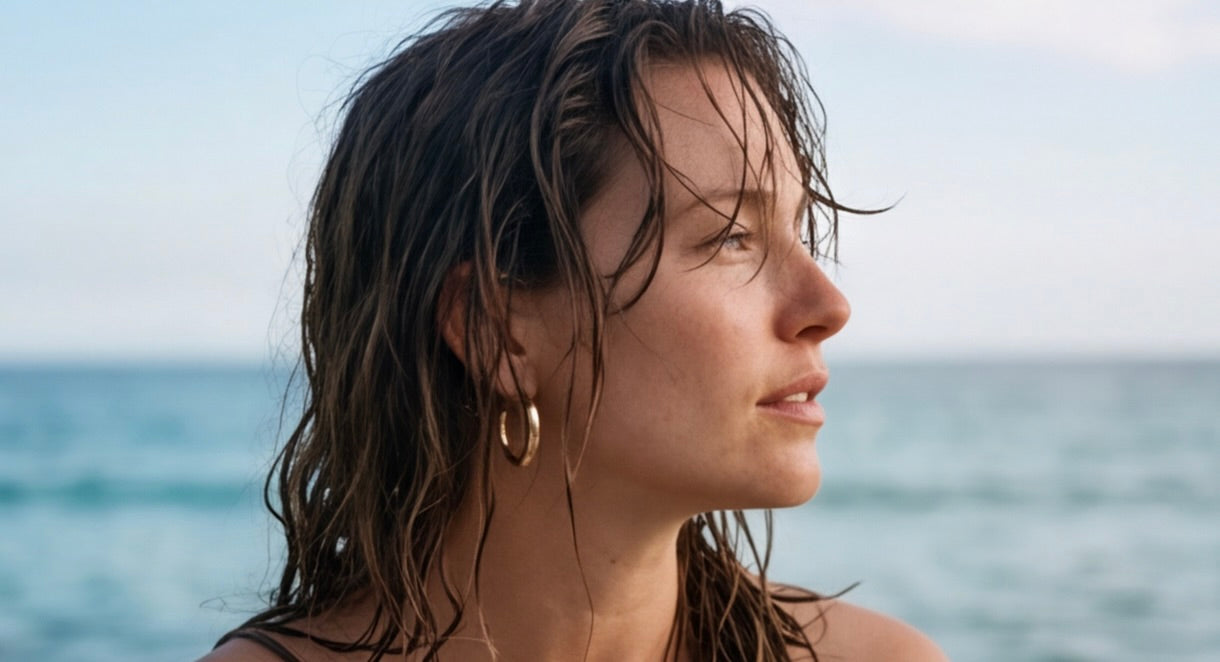 Woman with wet hair looking towards the ocean wearing Holly Hoops earrings from Delani Jewelry