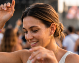 Close-up of woman smiling outdoors wearing gold Azizi Hoops chain earrings — tarnish-proof, waterproof, backed by Delani's lifetime color guarantee