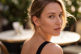 Woman with hoop earrings looking to the side outdoors wearing Frankie Hoops from Delani Jewelry