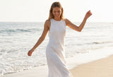 Woman wearing Delani Jewelry Kala Hoop Earrings while walking on the beach. Waterproof, tarnish-proof gold hoop earrings with a lifetime color guarantee for effortless everyday coastal style.