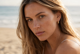 Close-up of Delani Jewelry Kala Hoop Earrings on a model featuring waterproof, tarnish-proof 18K gold PVD stainless steel and a lifetime color guarantee for everyday luxury wear.