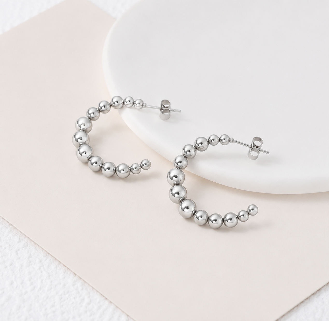 Silver hoop earrings on a white plate with a beige napkin from Delani Jewelry