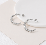 Silver hoop earrings on a white plate with a beige napkin from Delani Jewelry