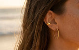 Kenza Cuff worn at the beach with gold hoop earring, waterproof tarnish-proof jewelry, lifetime color guarantee