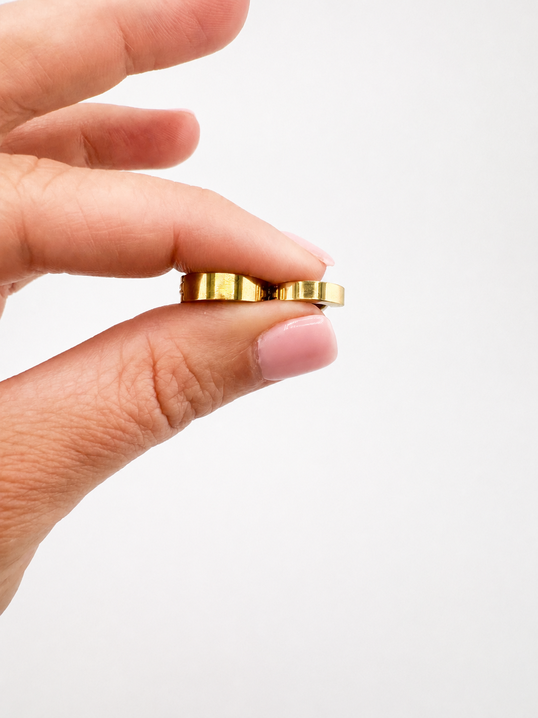 Hand holding the waterproof Kenza Cuff in gold, tarnish-proof jewelry with lifetime color guarantee in two different widths, small 3mm, medium 4mm