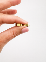 Hand holding the waterproof Kenza Cuff in gold, tarnish-proof jewelry with lifetime color guarantee in two different widths, small 3mm, medium 4mm