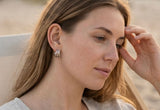 Natural beach lifestyle photo of Delani Jewelry Saja Hoop Earrings in silver. Waterproof, tarnish-proof earrings with a lifetime color guarantee and lightweight comfort.