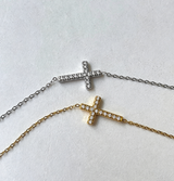 Two diamond-cross necklaces on a light gray background from Delani Jewelry