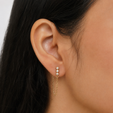 Close-up of the gold Shyla chain drop earring 3 stone side featuring a bezel-set crystal and elegant chain detail from Delani Jewelry. Waterproof, tarnish-proof, hypoallergenic, with a lifetime guarantee. Mismatched stones numbers create a drama and appeal unique to the Shyla Earrings. 