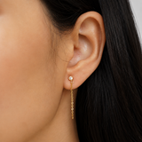 Close-up of Delani Jewelry's gold Shyla one-stone chain drop earrings with brilliant bezel-set crystals and delicate chain. Waterproof, tarnish-proof, hypoallergenic earrings with a lifetime guarantee. Mismatched stones numbers create a drama and appeal unique to the Shyla Earrings. 
