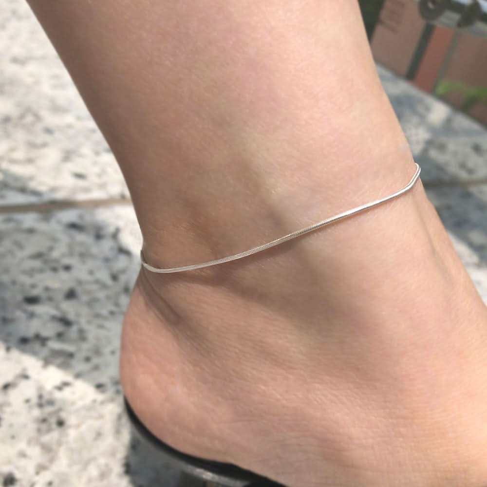 Delicate silver Lyra anklet from Delani Jewelry with small charm details, designed for ankle adornment.
